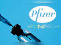 FILE PHOTO: Vial and sryinge are seen in front of displayed Pfizer and Biontech logo