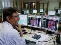 A broker laughs while speaking to a colleague, as they trade on their computer terminals at a stock brokerage firm in Mumbai