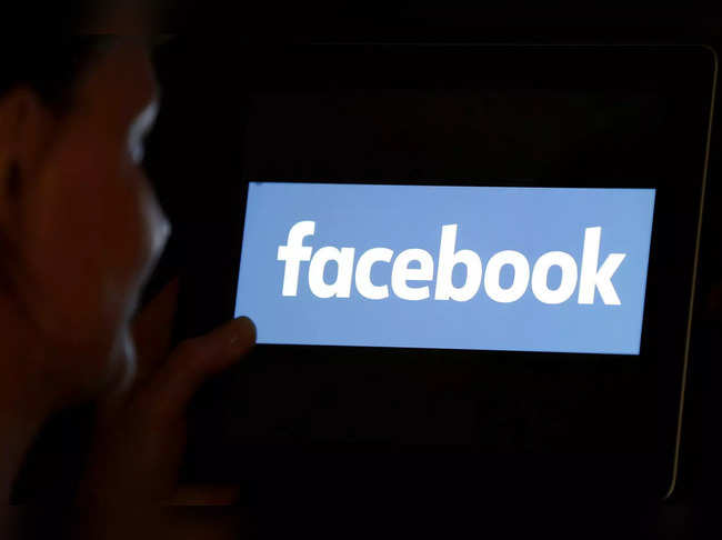 FILE PHOTO: A woman looks at the Facebook logo on an iPad in this photo illustration