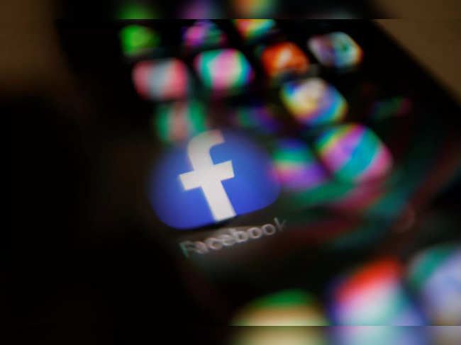 Facebook logo displayed on a mobile phone is seen through a magnifying glass in this picture illustration