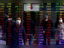 Pedestrians are reflected in an electronic board displaying various stock prices at a brokerage in Tokyo