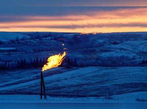 FILE PHOTO: A natural gas flare on an oil well pad burns as the sun sets outside Watford City, North Dakota