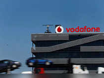 FILE PHOTO: A truck carrying cars speeds past the headquarters of Vodafone in Madrid