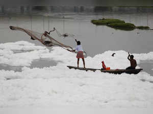 Man casts a fishing net into the polluted waters of the river Yamuna in New Delhi