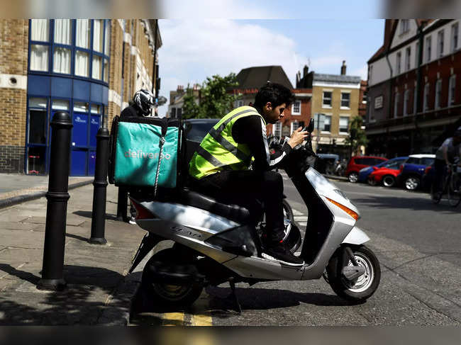 FILE PHOTO: A Deliveroo scooter driver takes a break between deliveries in London