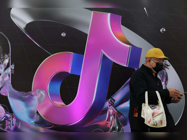 FILE PHOTO: Man stands near a giant sign of Chinese company ByteDance's app TikTok, known locally as Douyin, during China Fashion Week, in Beijing