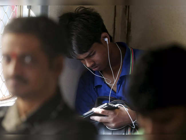 FILE PHOTO: A man watches a video on his mobile phone as he commutes by a suburban train in Mumbai