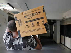 FILE PHOTO: A delivery worker of Amazon carries a packet to deliver it to a customer at a residential apartment in Ahmedabad