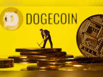 A small toy figure is seen on the cryptocurrency representation with Dogecoin logo in the background in this illustration