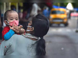 Kolkata: A woman adjusts the protective face mask of her child, at a deserted ro...