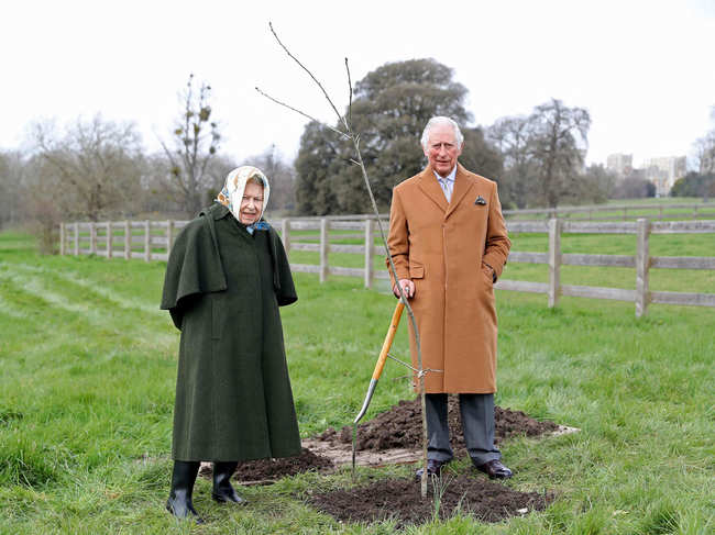 In this handout photograph taken on March 23, 2021 and released by Buckingham Palace on May 17, 2021, Britain's Queen Elizabeth II stands with her son Britain's Prince Charles, Prince of Wales in the grounds of Windsor Castle, after Charles planted a tree to launch The Queen's Green Canopy (QGC) tree-planting initiative created to mark The Queen's Platinum Jubilee in 2022.