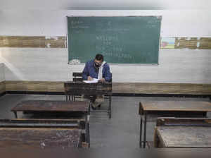A teacher waits for students in an empty classroom