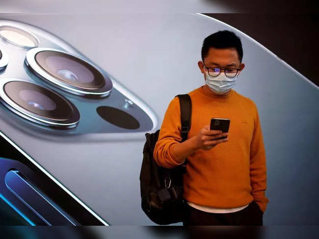 FILE PHOTO: A man wears a face mask while waiting at an Apple Store in Shanghai