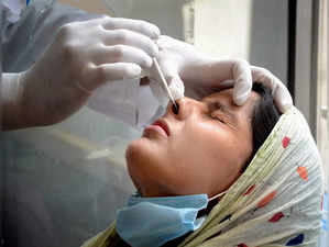 A health worker collects a swab sample of a woman for COVID-19 test