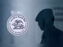 A security guard's reflection is seen next to the logo of the Reserve Bank Of India (RBI) at the RBI headquarters in Mumbai