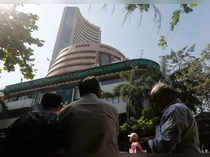 People watch a large screen displaying India's benchmark share index on the facade of the Bombay Stock Exchange building in Mumbai