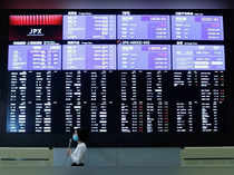 A TV reporter stands in front of a large screen showing stock prices at the Tokyo Stock Exchange after market opens in Toky