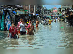 Kolkata: Pedestrians wade through a flooded road during landfall of cyclone 'Yaa...