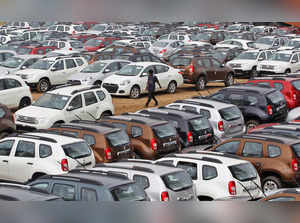 FILE PHOTO: A worker walks past parked Renault cars at its stockyard on the outskirts of Ahmedabad
