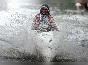 A person rides a scooter through a waterlogged road during monsoon rain showers in Mumbai
