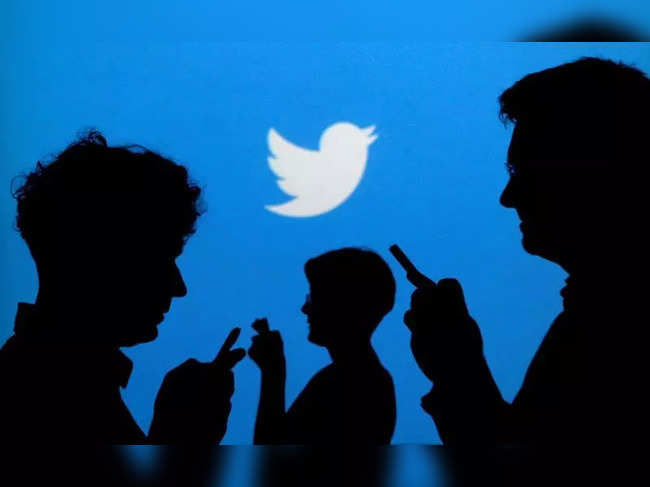 FILE PHOTO: People holding mobile phones are silhouetted against a backdrop projected with the Twitter logo