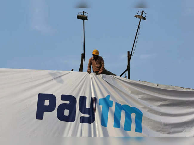 FILE PHOTO: A worker adjusts a hoarding of Paytm, a digital payments firm, in Ahmedabad
