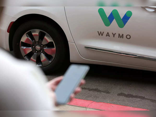 FILE PHOTO: A Waymo employee hails a ride on their phone during a demonstration in Chandler, Arizona