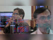 A broker watches a TV news channel as another monitors share prices at a brokerage firm in Mumbai