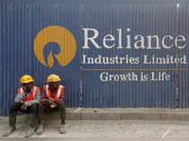 FILE PHOTO: Labourers rest in front of an advertisement of Reliance Industries Limited at a construction site in Mumbai