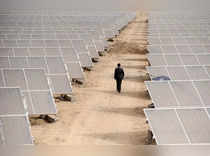 FILE PHOTO: A man walks through solar panels at a solar power plant under construction in Aksu