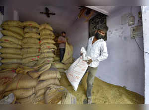 East Delhi: Labourers manage the sacks filled with free ration provided by the C...