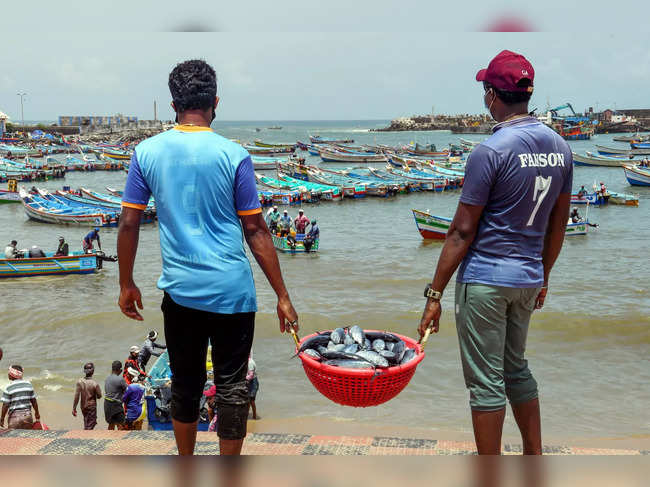 Thiruvananthapuram: Fishermen carry fish in a basket after authorities eased res...