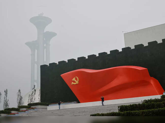 People stand in front of a giant red flag outside the Museum of the Communist Party of China that was opened ahead of the 100th founding anniversary of the Party in Beijing