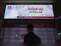 Hong Kong:A man walks past a bank's electronic board showing the Hong Kong share...