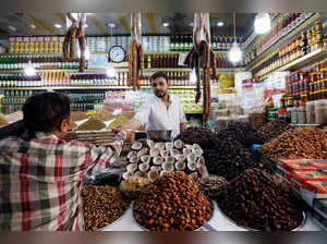 Shopkeeper serves a customer while selling dry fruits and grocery items along a market in Karachi