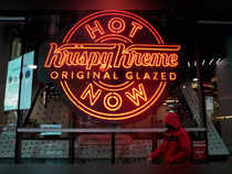 FILE PHOTO: A man walks past a Krispy Kreme "Hot Now" neon sign in Times Square in New York City