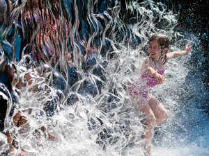 A young girl splashes through a waterfall at a park in Washington, DC AFP