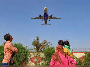 Ahmedabad: People look on as a passenger airplane approaches to land at a airpor...