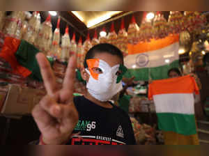 Jammu: A boy wearing a tricolour mask shows a victory sign at a shop ahead of th...