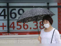 Tokyo: A woman walks by an electronic stock board of a securities firm in Tokyo....