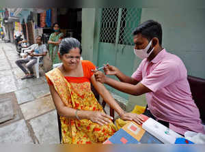 Woman reacts as she receives a dose of COVISHIELD vaccine in an alley at a slum area, in Ahmedabad