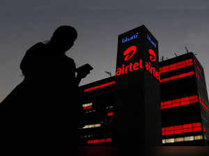 FILE PHOTO: A girl checks her mobile phone as she walks past the Bharti Airtel office building in Gurugram