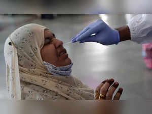 A health worker collects a swab sample from a traveler to test for COVID-19 at Chhatrapati Shivaji Maharaj Terminus in Mumbai, AP