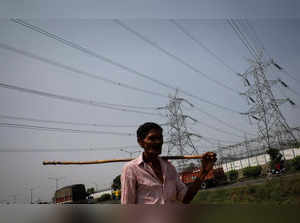 Man walks past electricity pylons on the outskirts of Ahmedabad