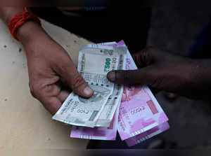 A customer hands Indian currency notes to an attendant at a fuel station in Mumbai