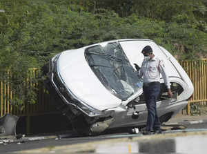 New Delhi: A policeman inspects the mangled remains of a car after an accident n...