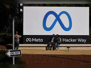 People pose in front of a sign of Meta, the new name for the company formerly known as Facebook, at its headquarters in Menlo Park