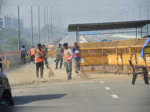 New Delhi: Workers sweep the road at Ghazipur border as barricades are removed f...