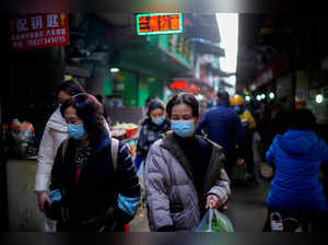 FILE PHOTO: FILE PHOTO: People wearing face masks walk on a street market, following an outbreak of the coronavirus disease (COVID-19) in Wuhan
