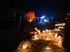 New Delhi: A child lights candles at the Singhu border farmers agitation site to...